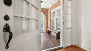 Una puerta que da a una habitación con suelo de baldosas, un banco y una pared de ladrillo.