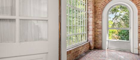 A room with a tiled floor, a white door, and a large window with a view of trees.