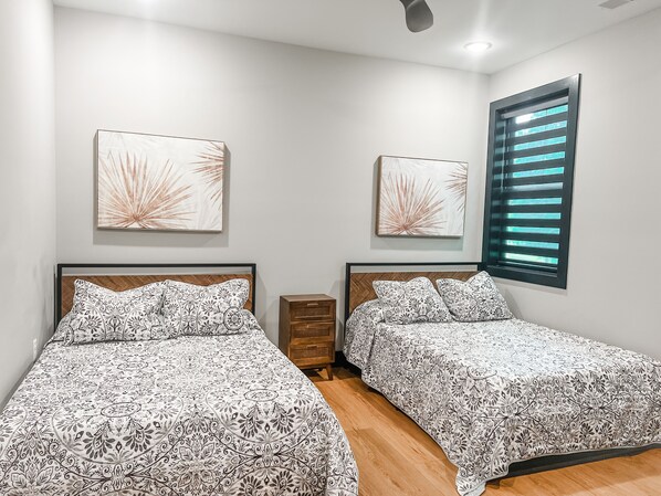 Habitación de hotel con dos camas, suelo de madera y obras de arte en las paredes.