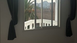 Een kamer met een groot raam, witte muren en een houten vloer.