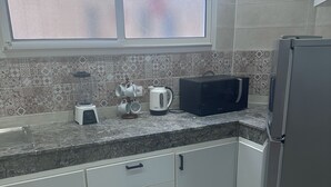 Een keuken met een koelkast, magnetron, waterkoker en blender op het aanrecht.
