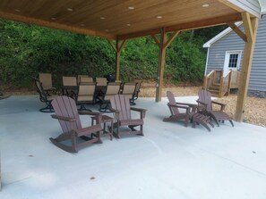 Eine Terrasse im Freien mit Adirondack-Stühlen und einer Holz-Pergola.