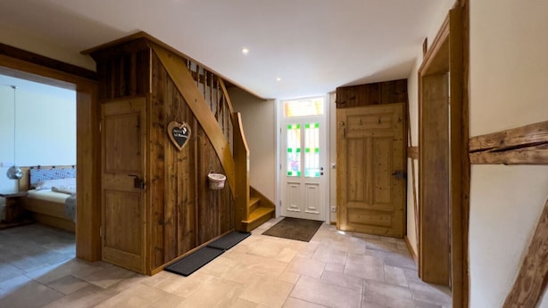 Un pasillo amplio con escaleras de madera, una cama al fondo y una puerta decorada con un corazón.