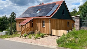 Una casa con techo inclinado, paneles solares y fachada de madera.