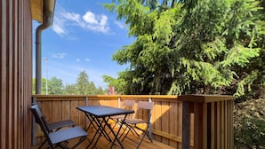Una terraza al aire libre con piso de madera, una mesa y dos sillas.