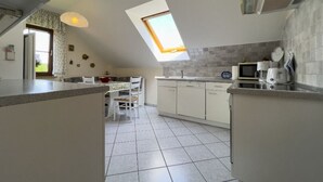 Eine Küche mit Oberlicht, weißen Schränken und einem Essbereich mit Stühlen.