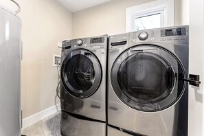 A laundry room with two front-loading LG washing machines, a white door, and a window above the machines. - Waterfront, Firepit, Kayak, Game room, Potomac 2hrs from DC, Dogs+EV OK (Montross)