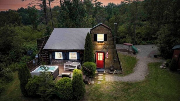 A rustic cabin with a red door, a hot tub, and a deck. - A-Frame Hot tub Retreat - Firepit, Grill, EV & Dog Friendly, Close to N. Conway. (Fryeburg)
