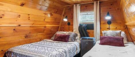 Una camera da letto accogliente in una baita, con due letti, pareti in legno e una finestra.