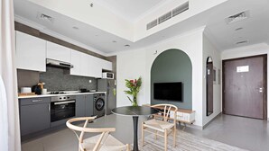 Una cocina moderna con armarios grises, un microondas y una estufa. Hay una mesa redonda con sillas y una planta en maceta.