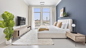 Un dormitorio moderno con una cama grande, televisor, una planta y vistas a la ciudad a través de amplios ventanales.
