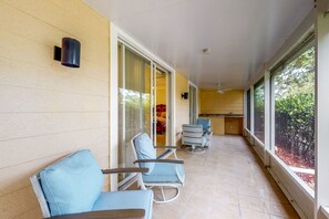 Relax in this tranquil outdoor seating area, featuring a glass door leading to the interior and a view of lush greenery.