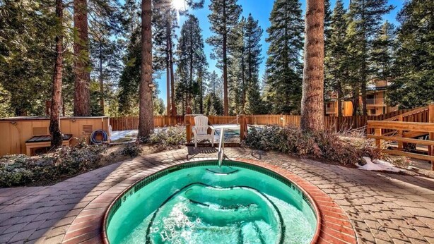 A hot tub surrounded by a wooden deck, with a wooden fence and tall trees in the background. - Alpine Alcove Near Kings Beach - Private Sleeping Nook - Pet Friendly (Tahoe Vista)