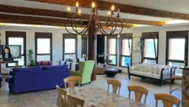 A spacious living area with a dining table, chairs, sofas, and a chandelier.