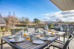 A wooden dining table set with white dishes, cups, and a glass of orange juice on a balcony overlooking a residential area. - Vantage Point, Hillfield Village (Dartmouth)
