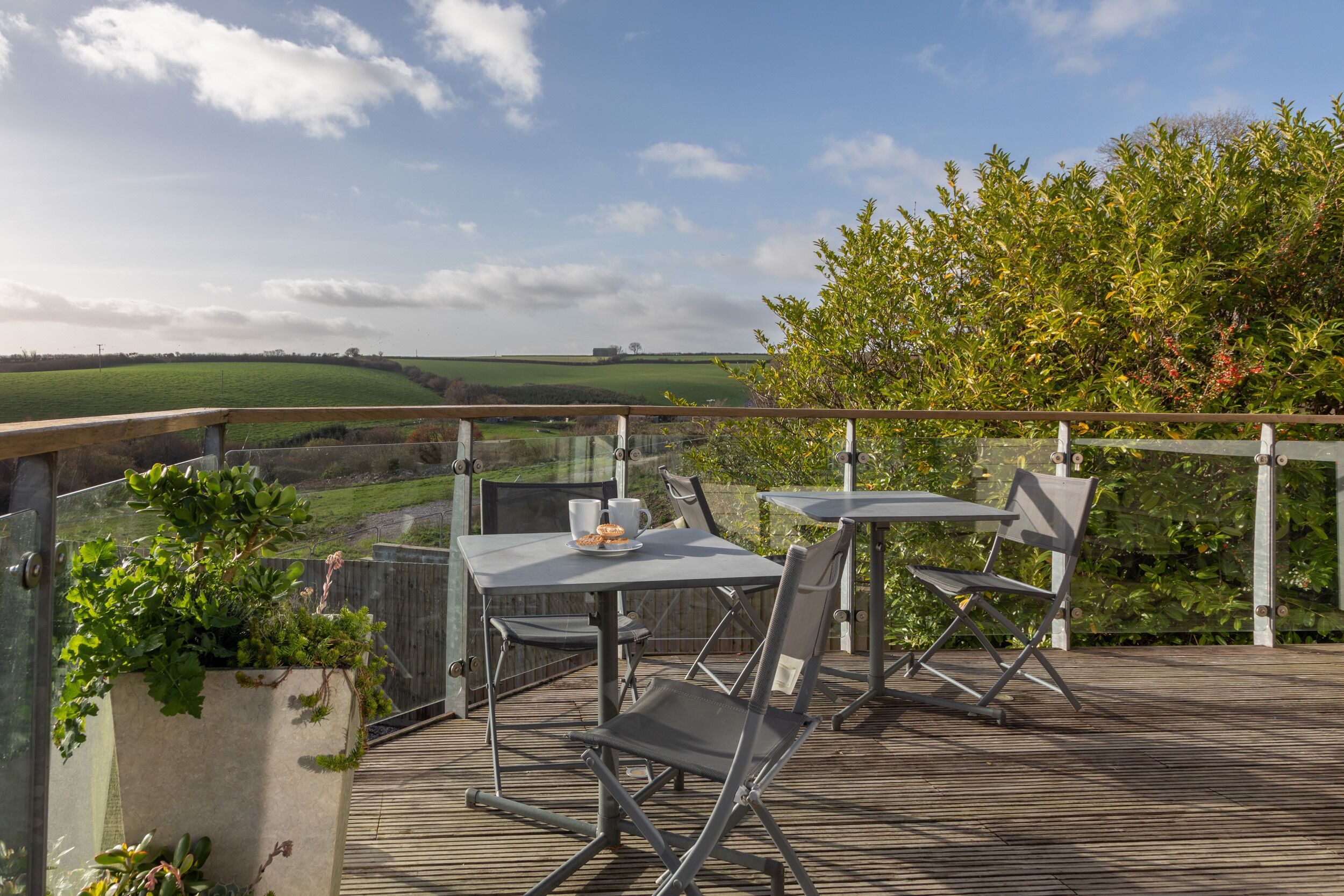 Une terrasse extérieure avec une table et des chaises, donnant sur un paysage verdoyant.