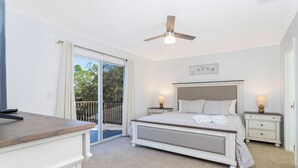 A bedroom with a bed, bedside tables, a ceiling fan, and a view of the outdoors. - Beautiful 5Bd Single Family w Game Room 106 Lake Wilson Preserve (Davenport)