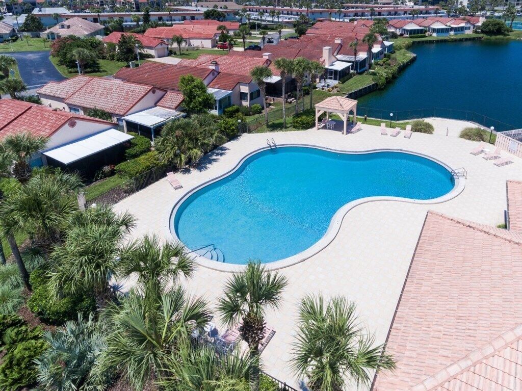 Una piscina de borde curvo, rodeada de palmeras y un pabellón.