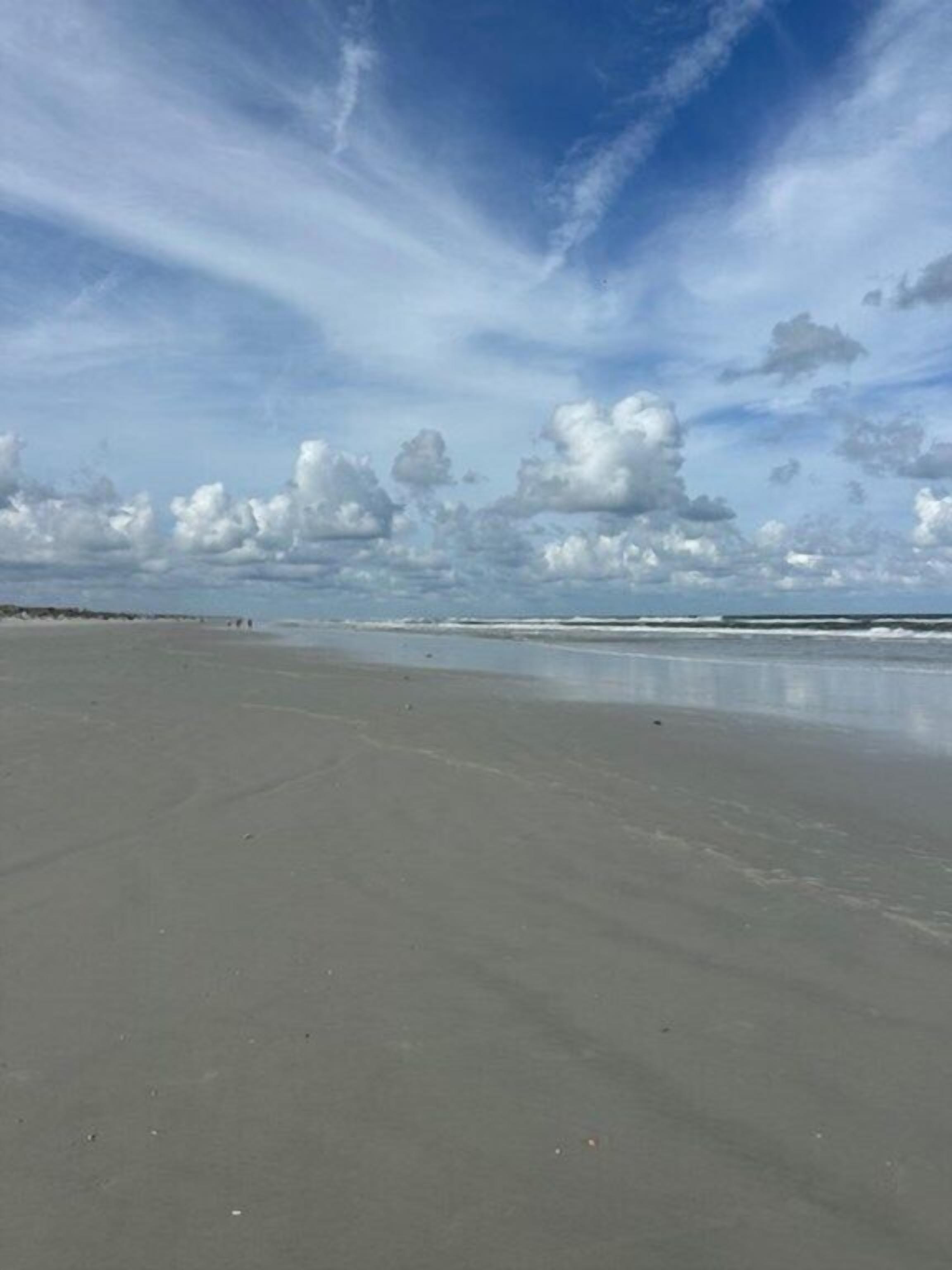 A wide, open beach with a clear sky and distant horizon.