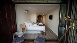 A hotel room with a bed, two chairs, a small stool, and a telescope. - Mister C Guest House (Hartbeespoort)