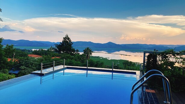A swimming pool with a view of a river and mountains. - Mister C Guest House (Hartbeespoort)