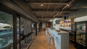 A bar area with stools, a counter, and a refrigerator stocked with bottles. - Mister C Guest House (Hartbeespoort)