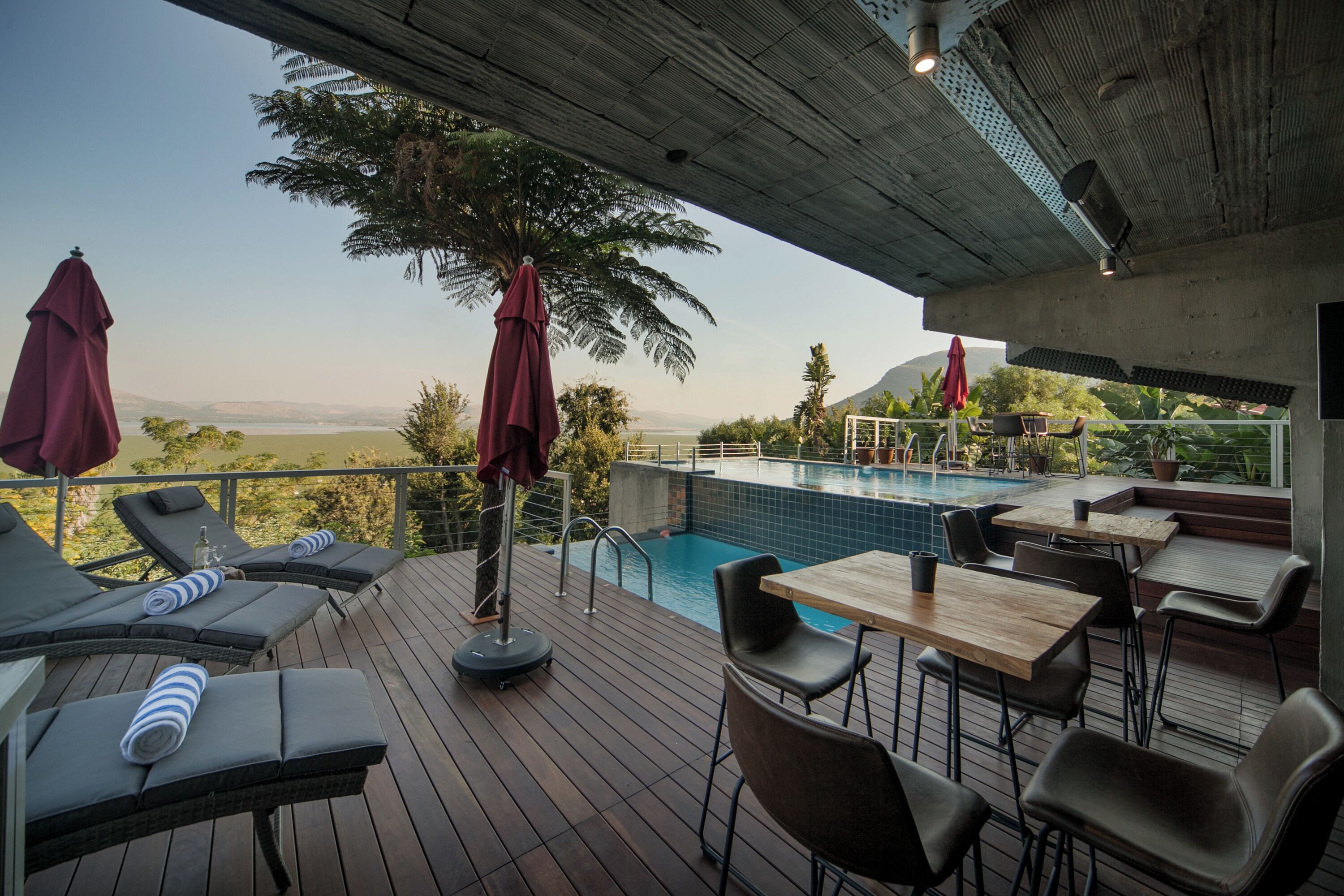 Zona junto a la piscina con sillones de descanso, una piscina y mesas.