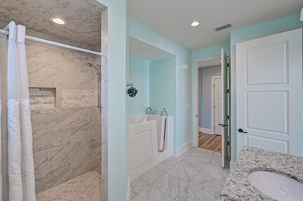 A modern bathroom with a walk-in shower, a bathtub, and a sink.