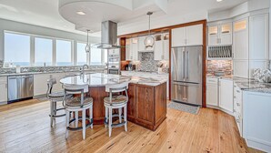 A modern kitchen with a central island, stainless steel appliances, and large windows. - Ocean Paradise (St. Augustine)