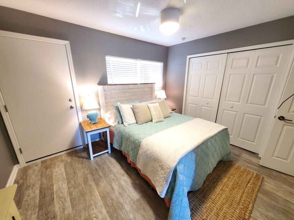A bedroom with a bed, nightstand, lamp, and a large closet.