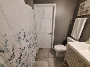 Un baño con una puerta blanca, un inodoro, un lavabo y un perchero para toallas.