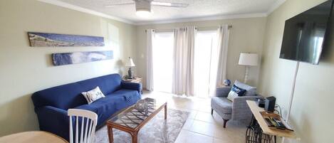 A living room with a blue sofa, a coffee table, a TV, and a ceiling fan.