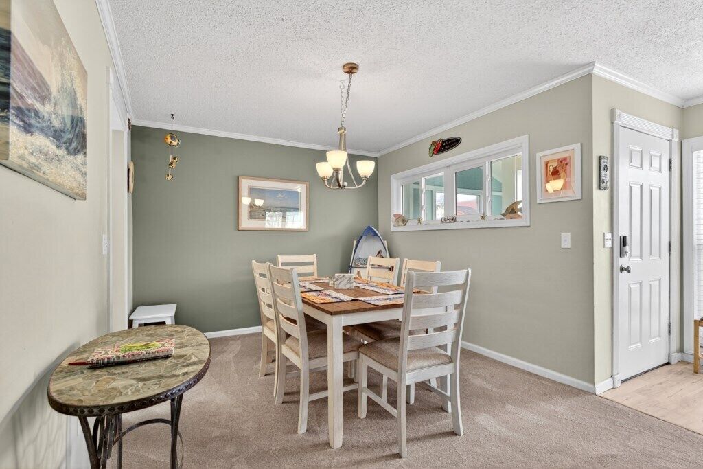 A dining area with a wooden table and chairs, a chandelier, and framed artwork on the walls.