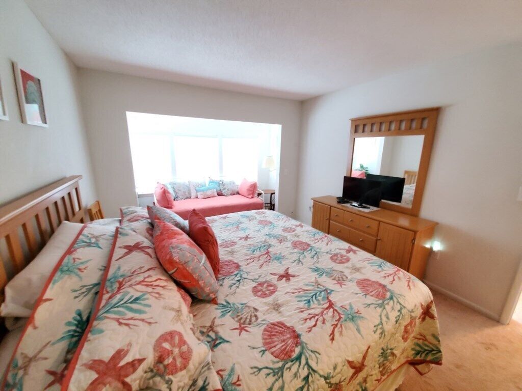 Un dormitorio con una cama, un aparador, un televisor y una ventana.
