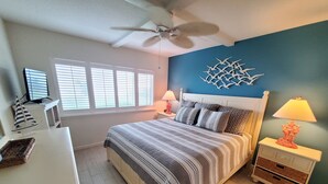 A bedroom with a bed, bedside tables, a ceiling fan, and a window with blinds. - Summerhouse 104 (St. Augustine)