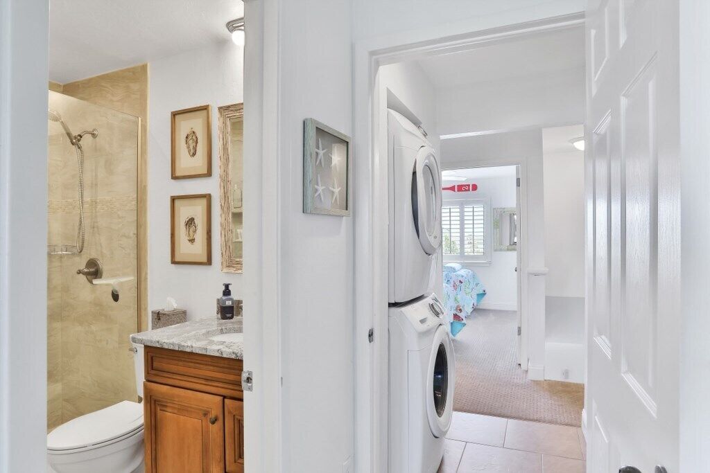 Une buanderie équipée d’un lave-linge et d’un sèche-linge, d’une douche et de toilettes.