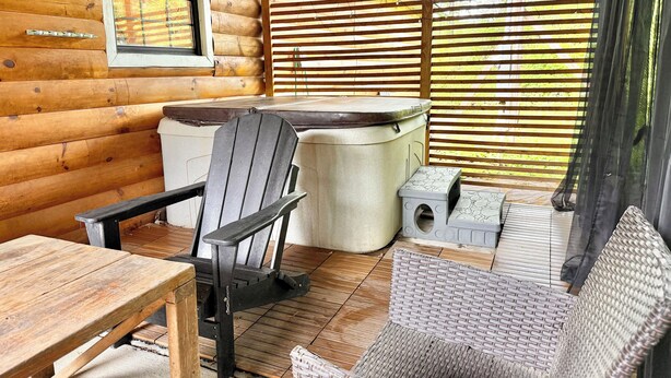 A wooden cabin interior with a wooden table, a chair, a sofa, and a hot tub. - 5 min from Parkway. Cozy cabin! (Sevierville)