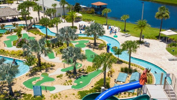 A pool area with a water slide, a putting green, and a view of a body of water. - Stunning 2Bd Apto Close to Disney Storey Lake 105 3171 (Kissimmee)