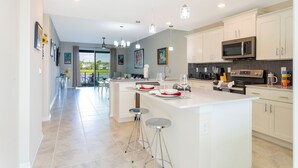 A modern kitchen with white cabinets, a large island, stainless steel appliances, and pendant lighting. - Stunning 2Bd Apto Close to Disney Storey Lake 105 3171 (Kissimmee)