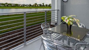 A balcony with a table and chairs, a potted plant, and a clock on the wall. - Stunning 2Bd Apto Close to Disney Storey Lake 105 3171 (Kissimmee)