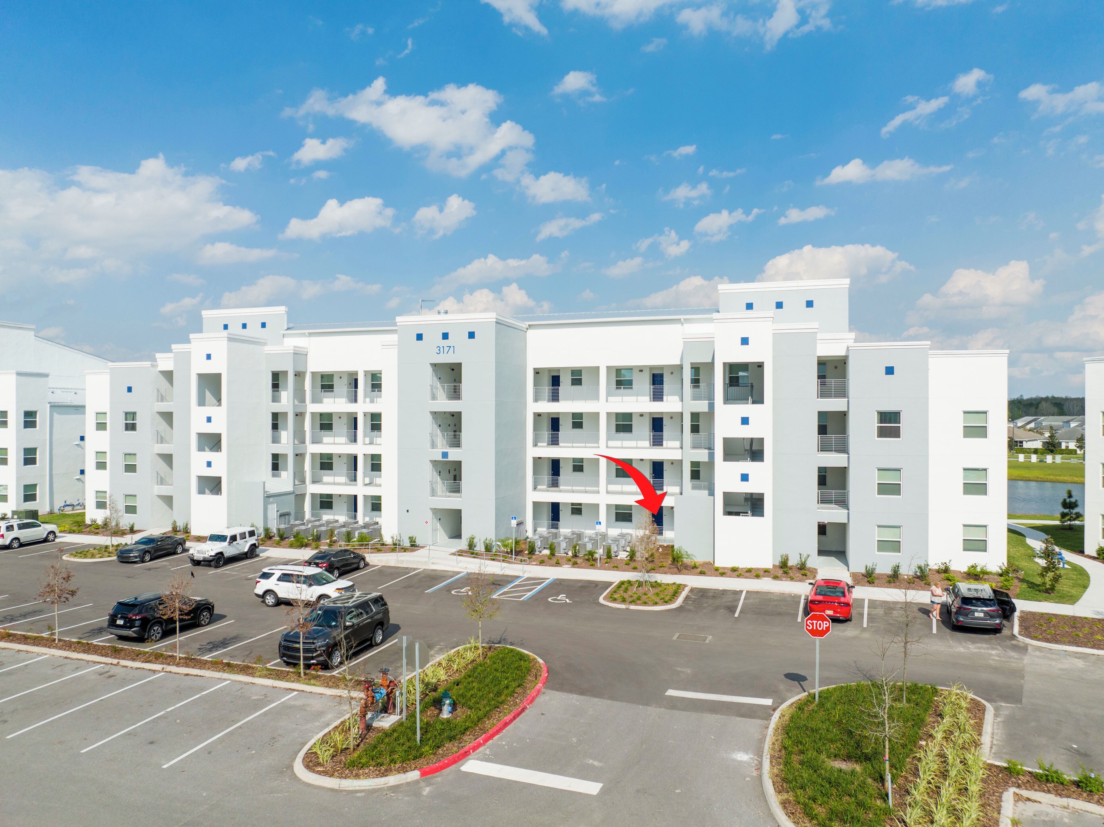 A modern multi-story building with a parking lot in front.