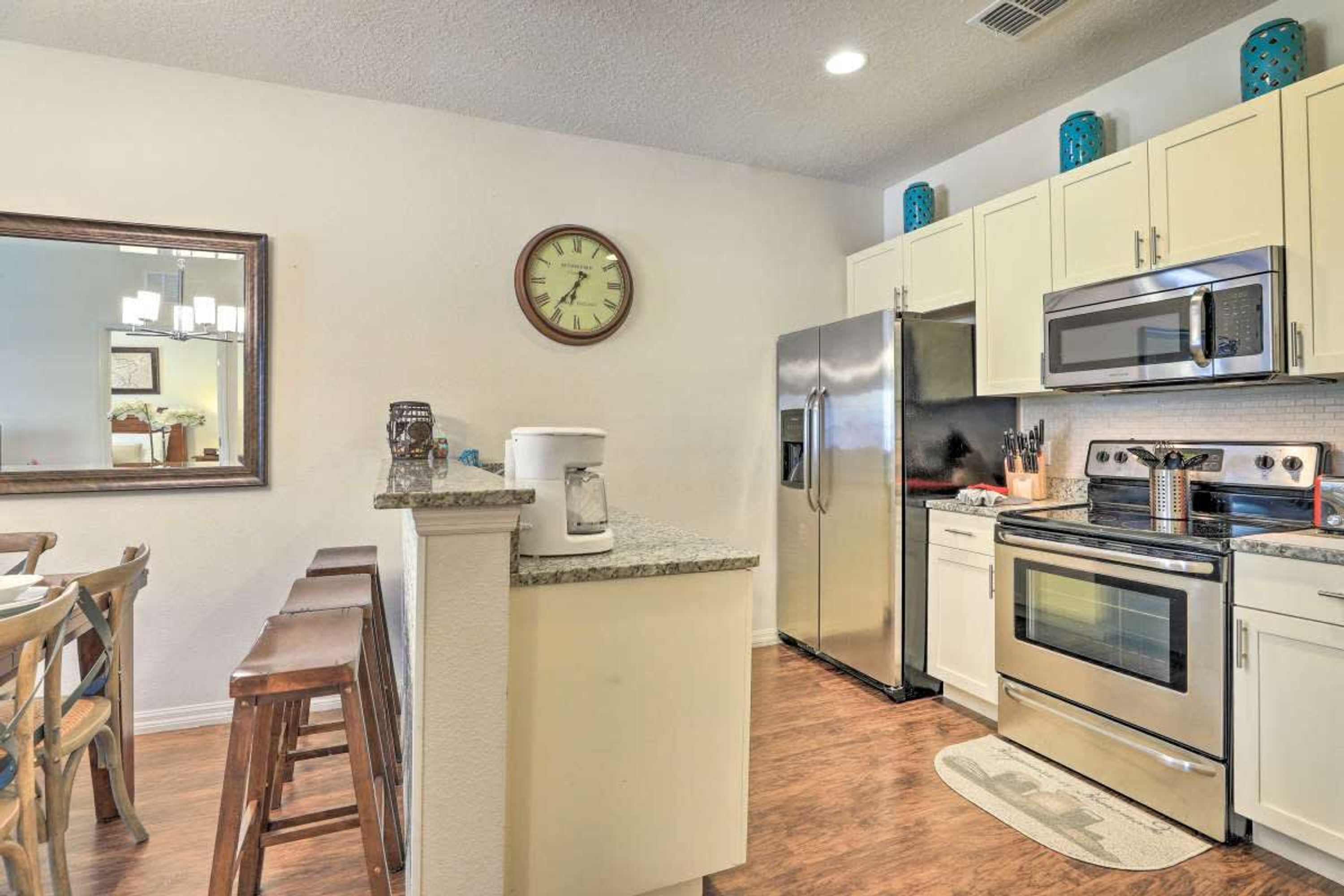 A kitchen with a central island, stainless steel appliances, and wooden bar stools.