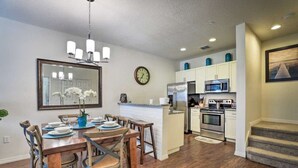 A modern kitchen with white cabinets, stainless steel appliances, and a dining area with a wooden table and chairs.