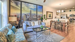 A modern living room with a sofa, coffee table, and a cityscape painting.