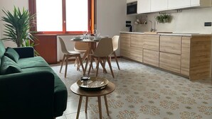 Un espace de vie compact comprenant un coin repas, une cuisine et un canapé vert.