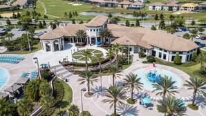 An aerial view of a resort with a central courtyard, multiple swimming pools, and a golf course in the background. - Stunning 5 Bd w Pool Close to Disney Champions Gate 1012 (Davenport)
