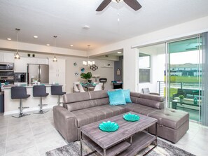 Relax in a spacious living area with a comfortable sofa and coffee table, adjacent to a well-equipped kitchen and dining area with a view of the surrounding landscape.