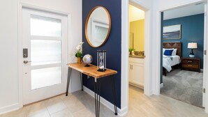 Een hotelkamer met een houten console tafel, een ronde spiegel, een wereldbol en een kleine plant.