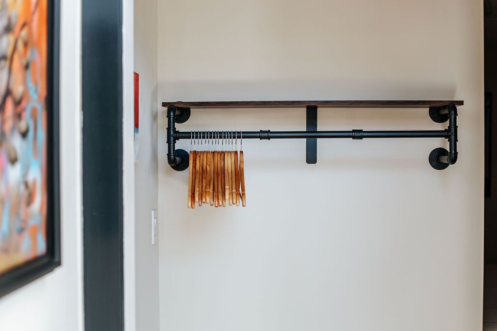 Una estructura metálica con una barra horizontal y un soporte vertical, sosteniendo varios objetos de color cobre.