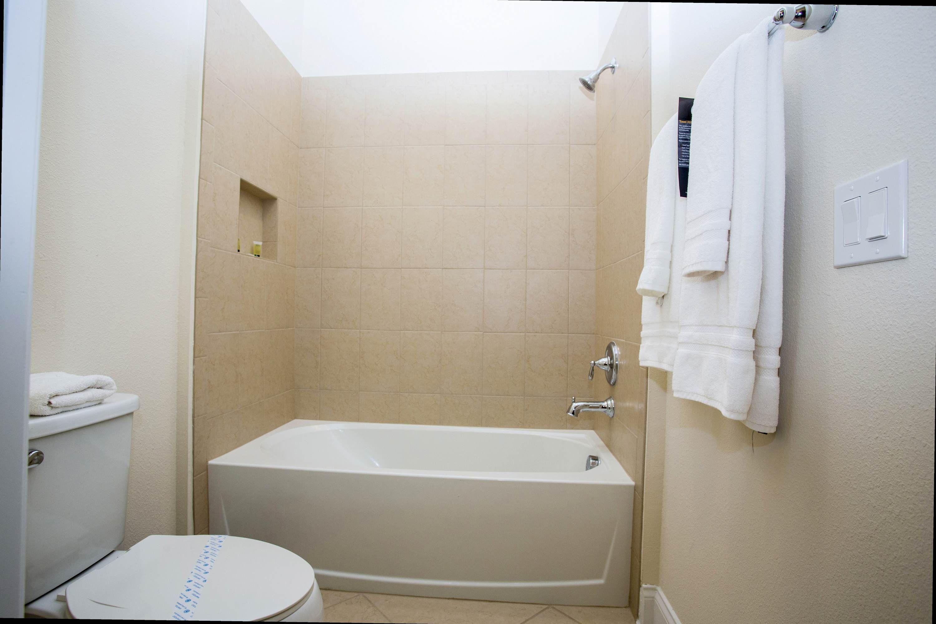 A bathroom with a bathtub, toilet, and a towel rack.